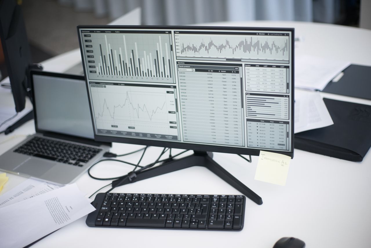 A polished workplace with computers and analytical charts displayed on a monitor, reflecting a contemporary business setting.